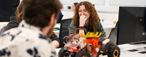 NMITE Students sat in a studio working on their mechatronics module. A remote control car is in front of them.